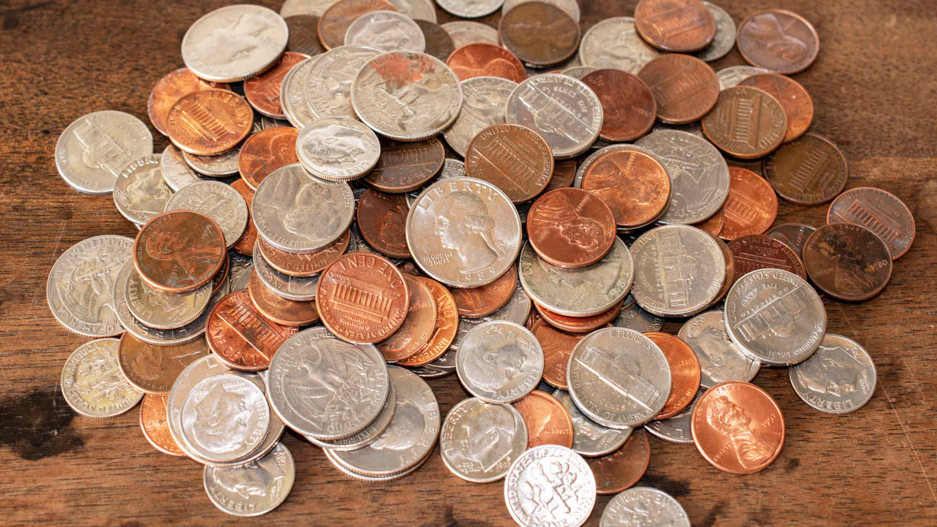 A Pile Of Coins On A Wooden Table