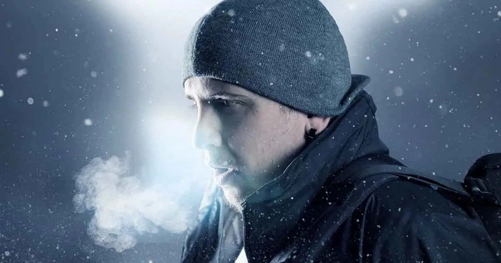 A Man In A Beanie And Hat Is Smoking In The Snow Wallpaper