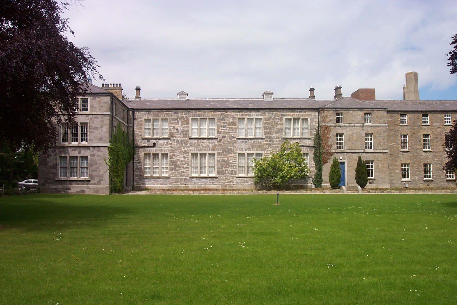 A Large Stone Building With A Green Lawn