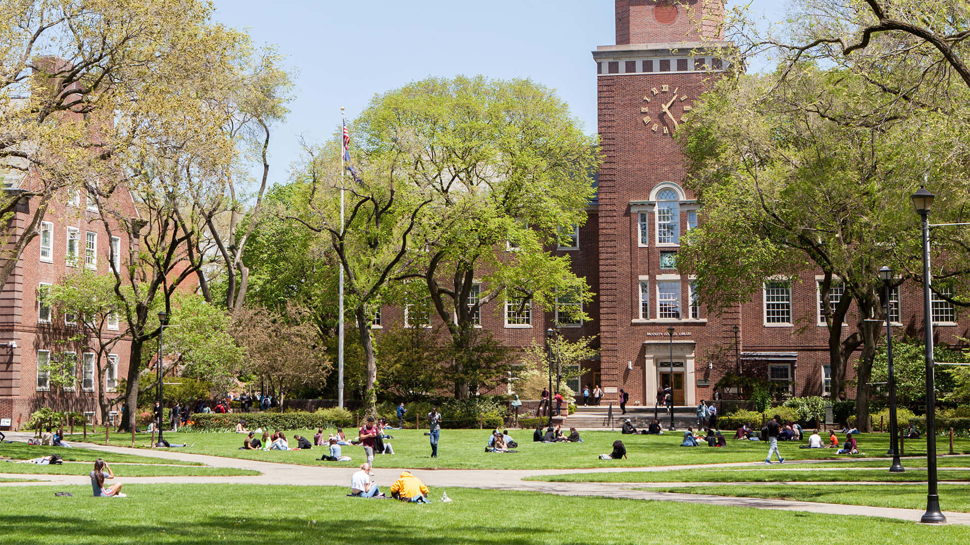 A Large Campus With Many People Sitting On The Grass
