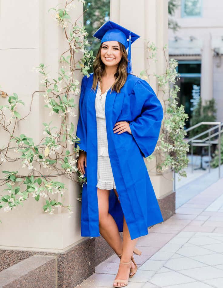 Download A Young Woman In A Blue Graduation Gown Leaning Against A Wall ...