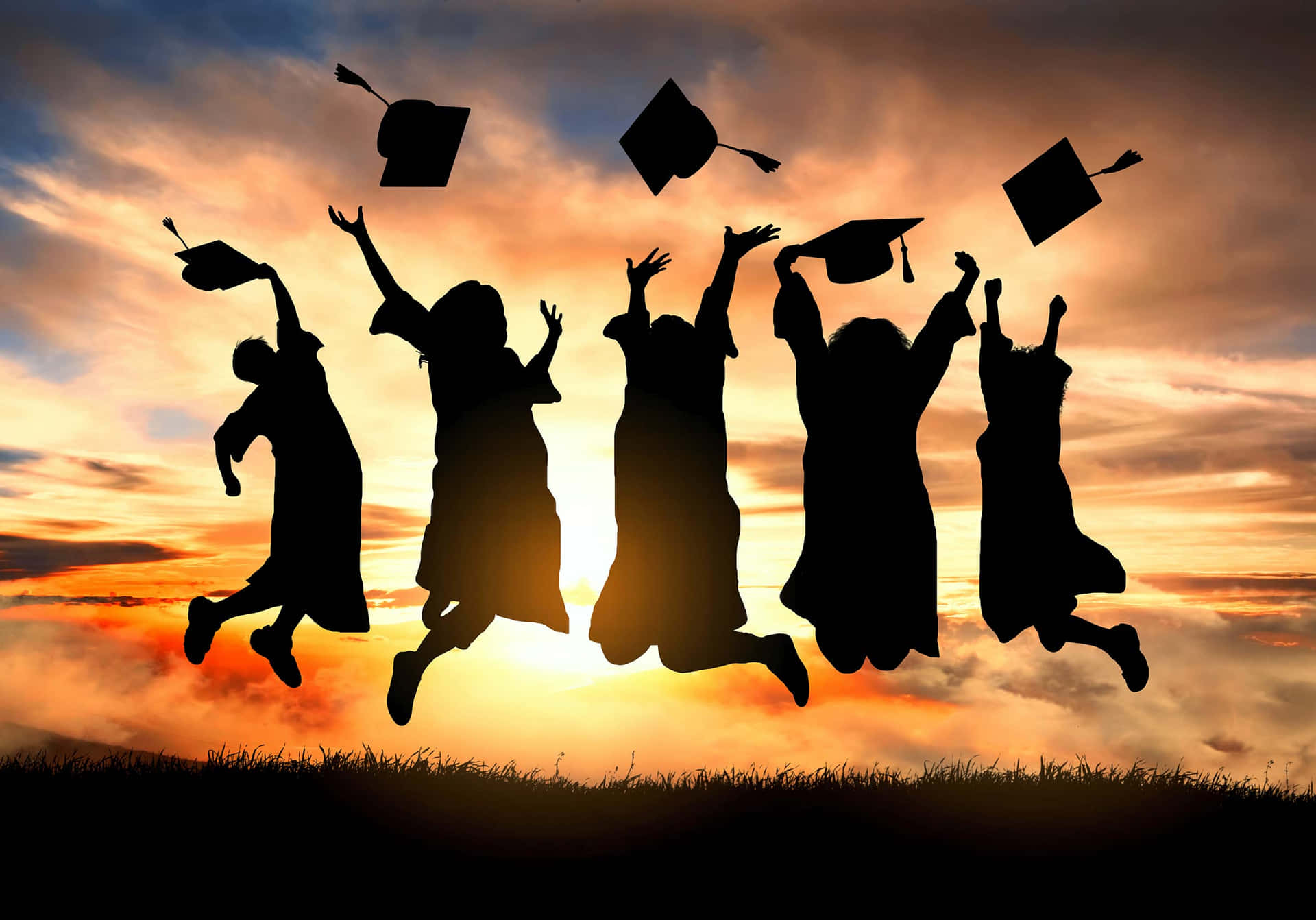 Silhouettes Of Graduates Jumping In The Air
