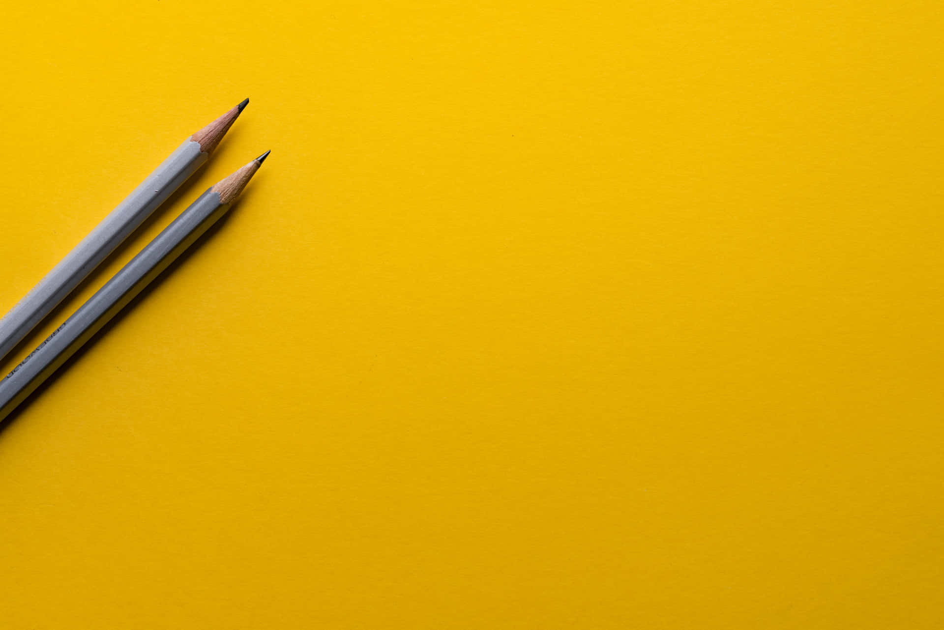 Two Grey Pencils On Yellow Table Color Background