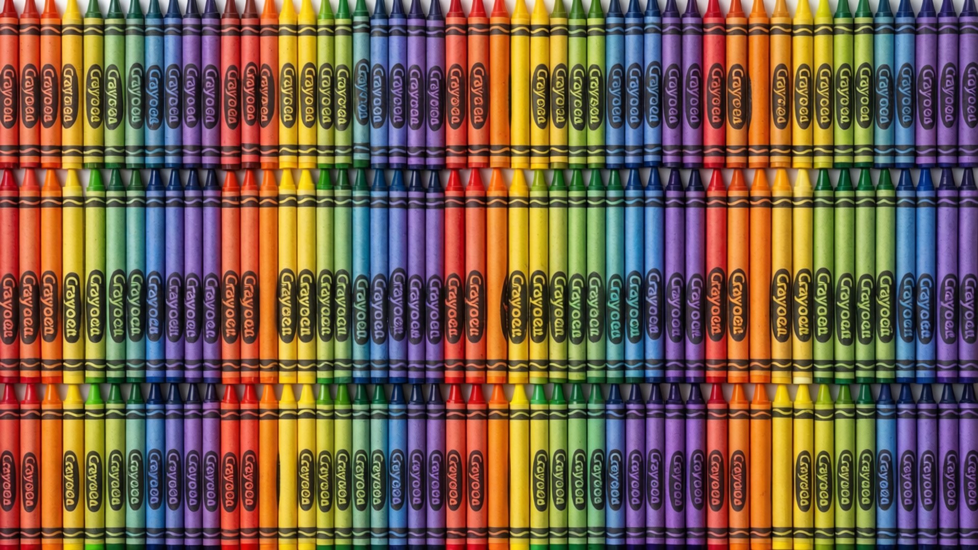 Seamless pattern wallpaper of Crayola crayons in a color gradient.