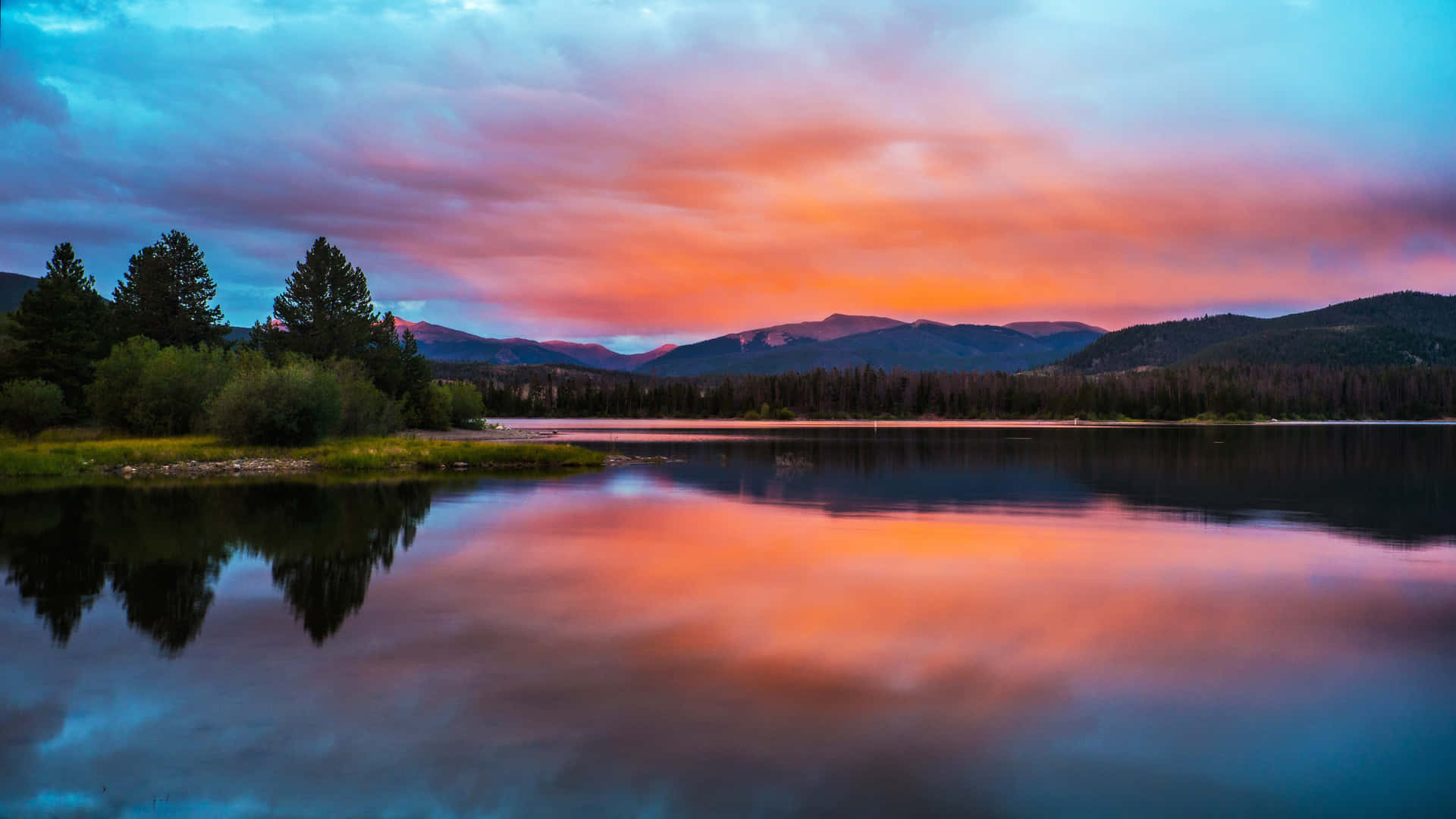 A Colorful Sunset Over A Lake And Mountains