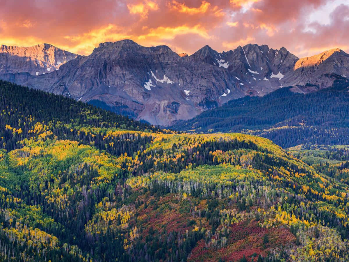 A Mountain Range With Colorful Trees And Mountains In The Background