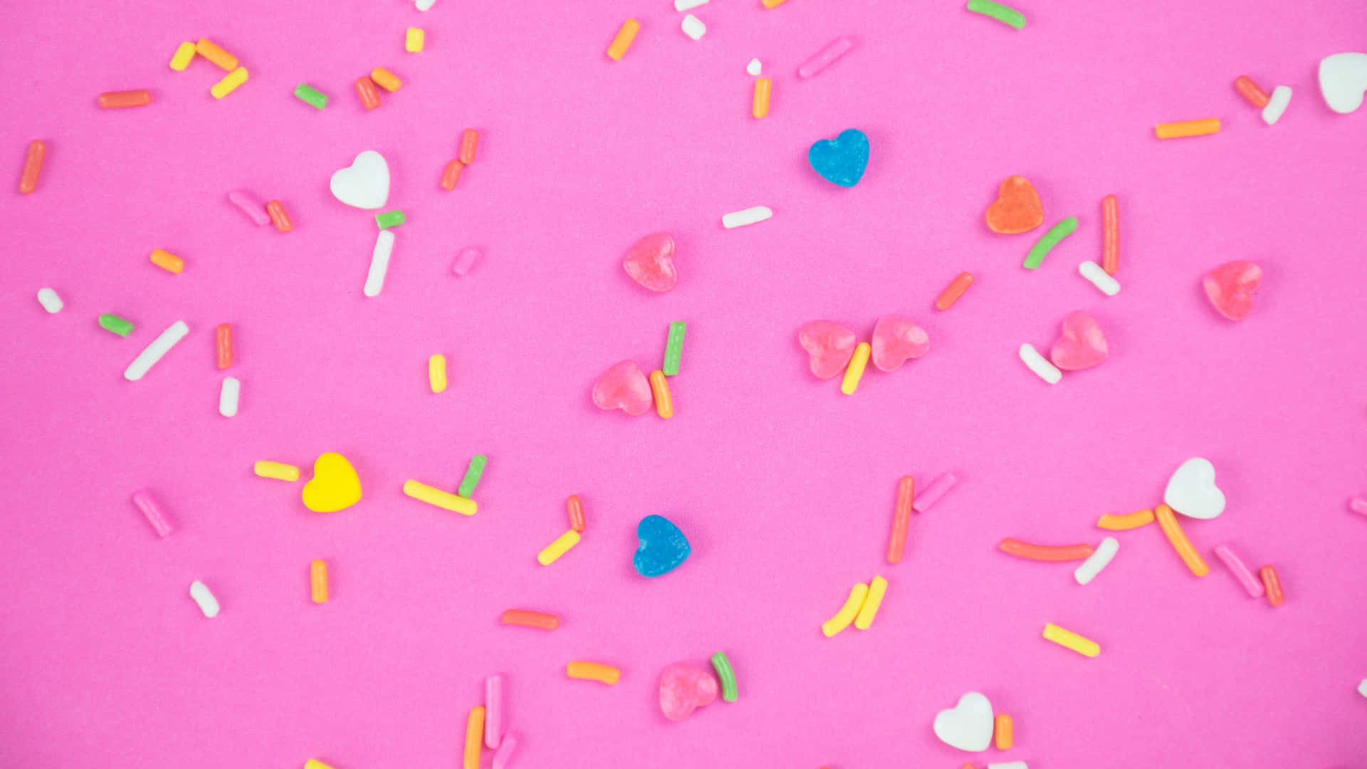 Colorful Candy Sprinkleson Pink Background Wallpaper