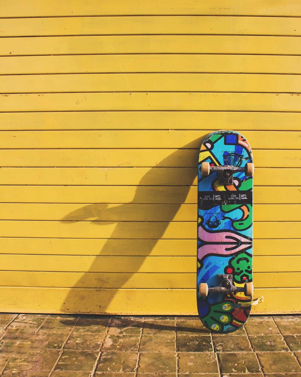 Colorful Skateboard Against Yellow Wall Wallpaper