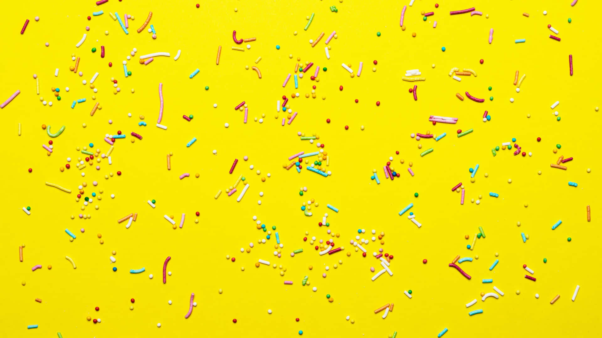 Colorful Sprinkleson Yellow Background Wallpaper