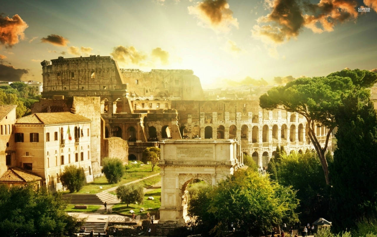 Colosseum Surrounded By Nature Beneath The Sunlit Sky Wallpaper