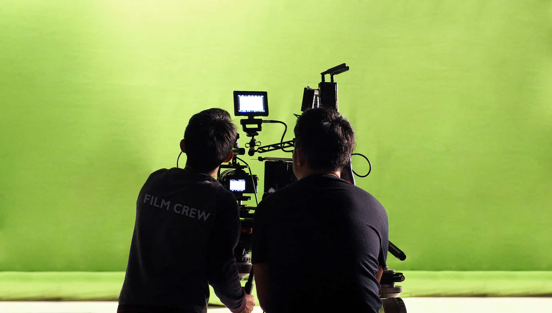 Professional Cameramen at Work in a Green Screen Studio Wallpaper