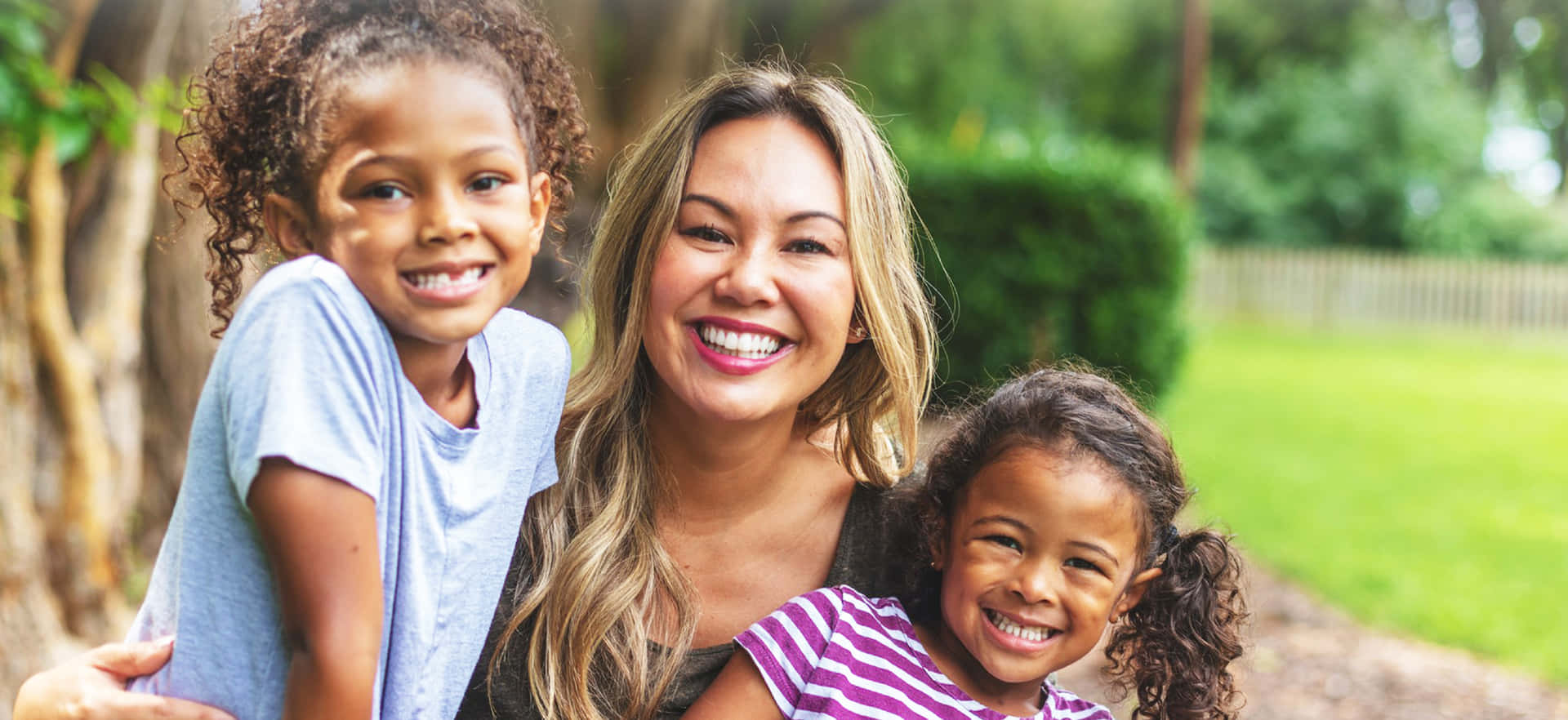 A Woman And Her Two Young Daughters Are Smiling