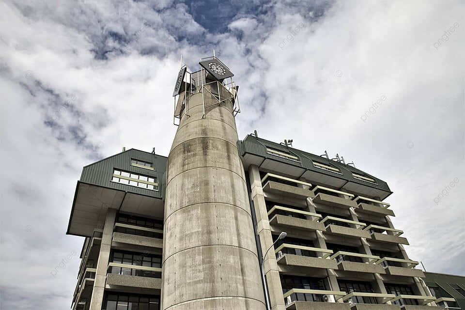 Concrete_ Tower_with_ Clock_ Under_ Cloudy_ Sky Wallpaper