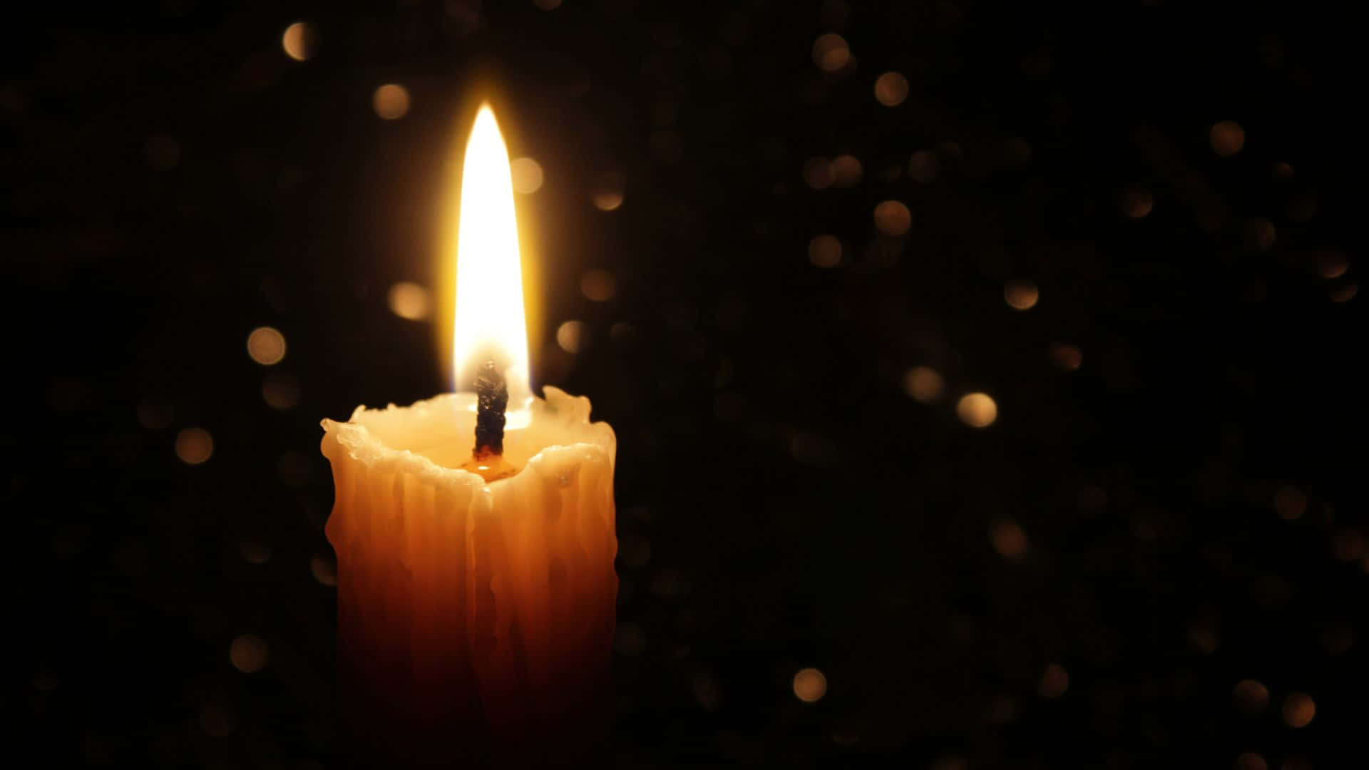 A Candle Lit In The Dark With A Black Background