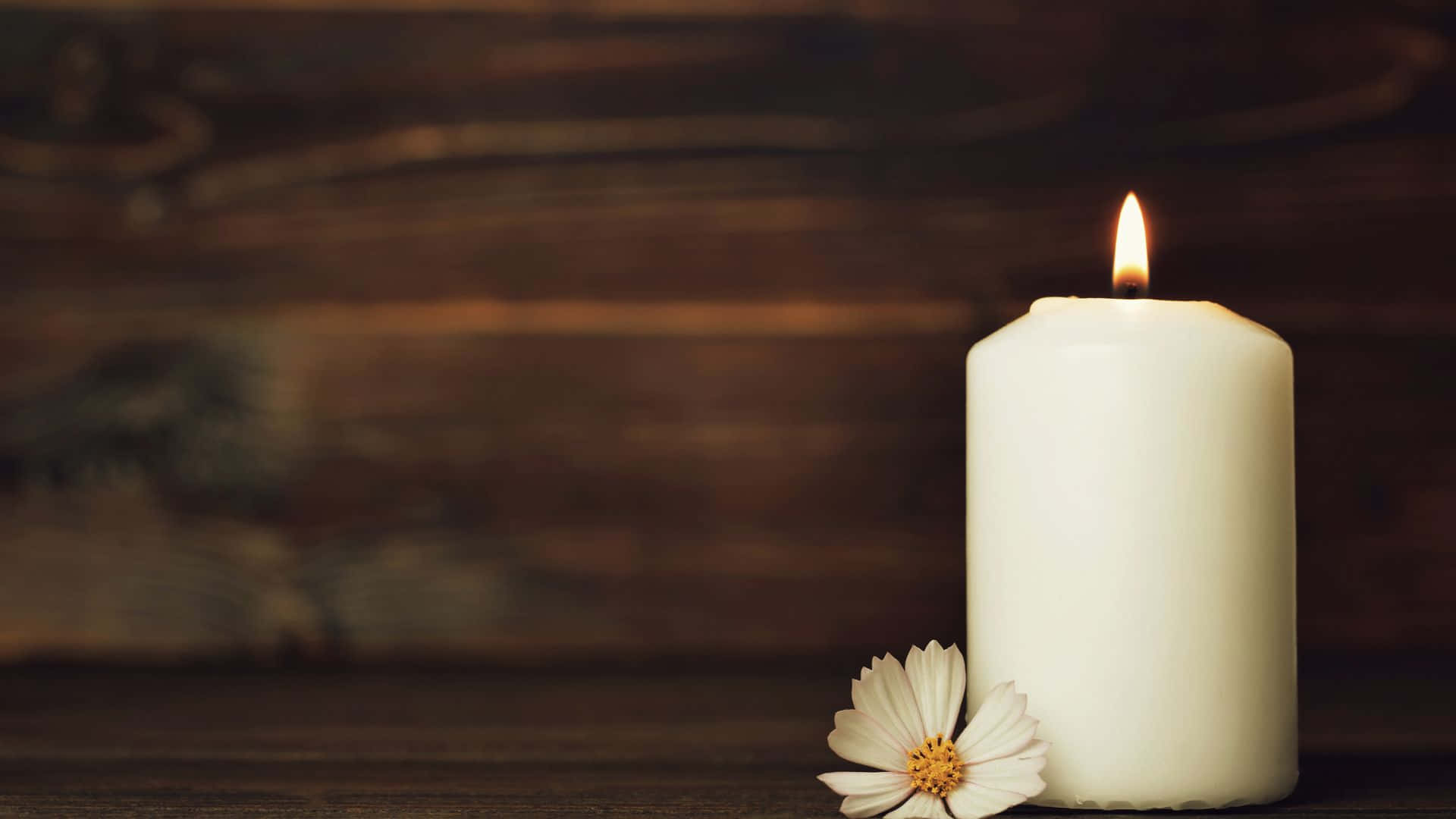 A Candle With A Flower On A Wooden Table