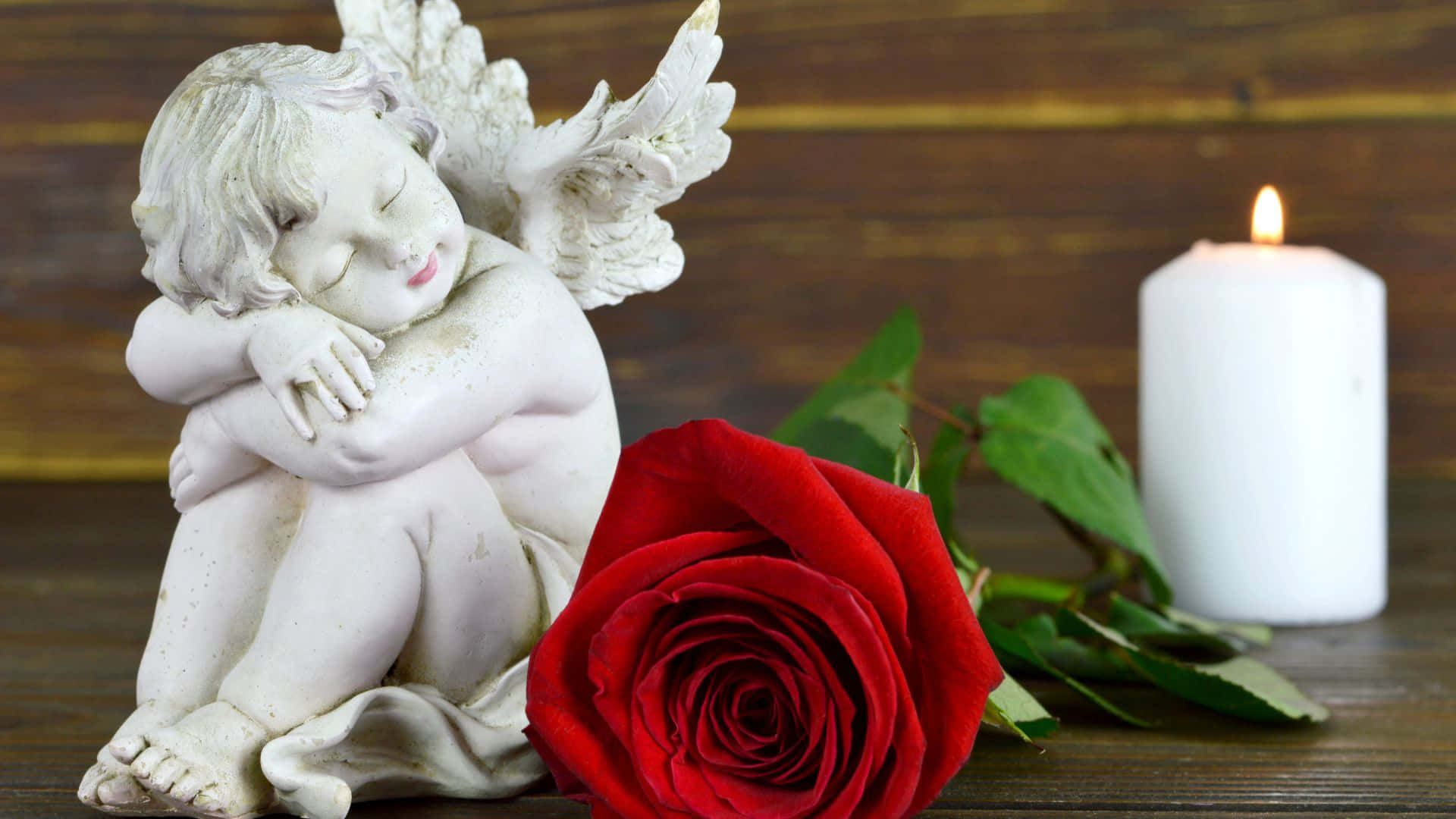 A Statue Of An Angel With A Red Rose