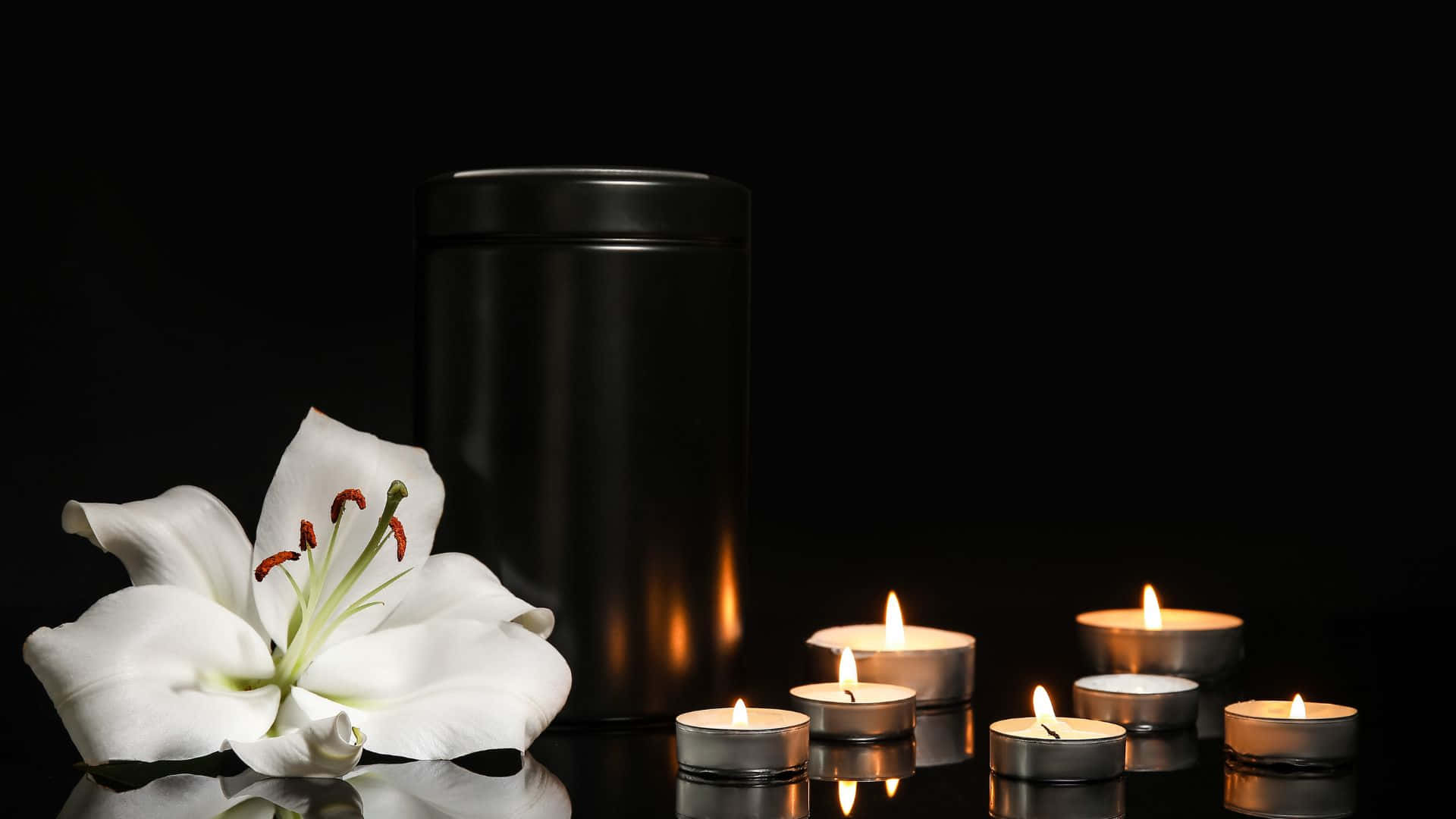 A Black Urn With Candles And A White Lily