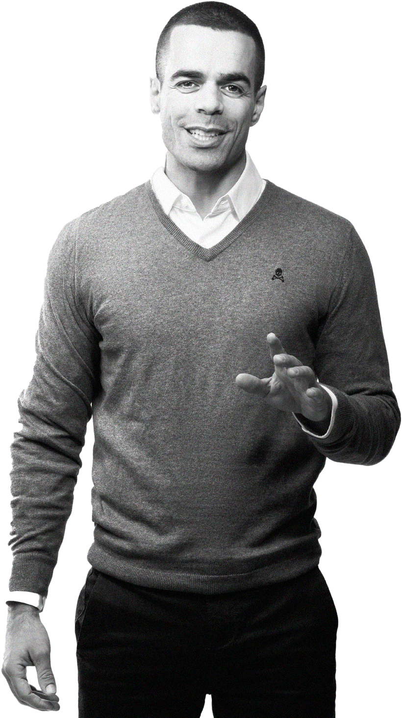 Confident Man Gesture PNG — A smiling man in a v-neck sweater gestures warmly against a stark black background.