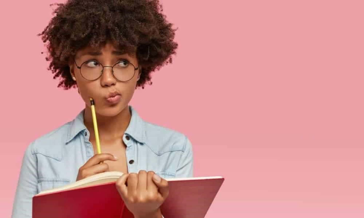 A Girl With Glasses Is Holding A Notebook And Pencil