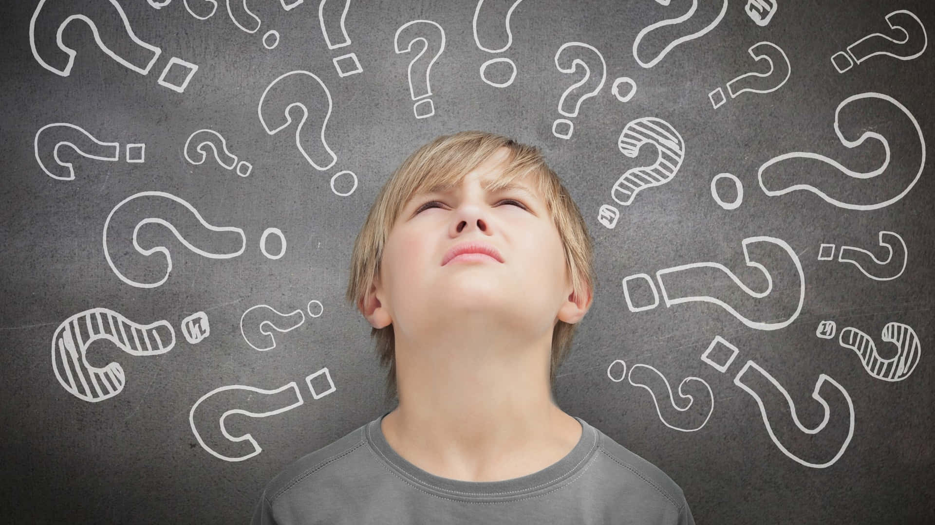 A Boy Looking Up At Question Marks