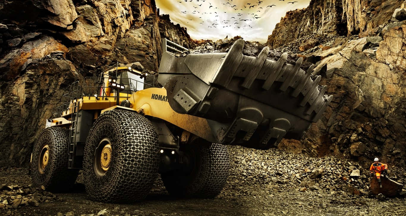A Large Yellow Truck Is Driving Through A Rocky Area