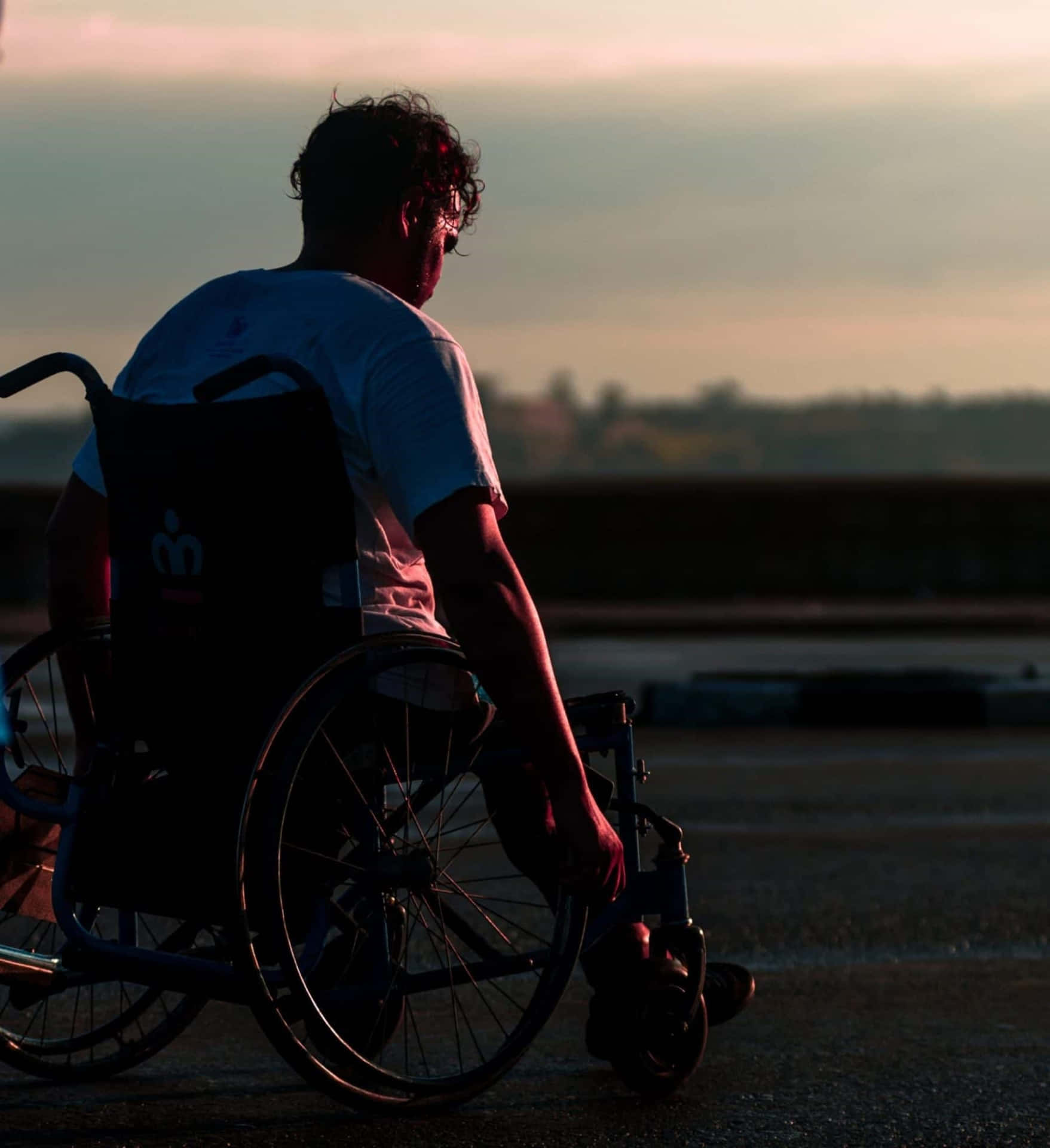 Contemplative Wheelchair Userat Sunset Wallpaper