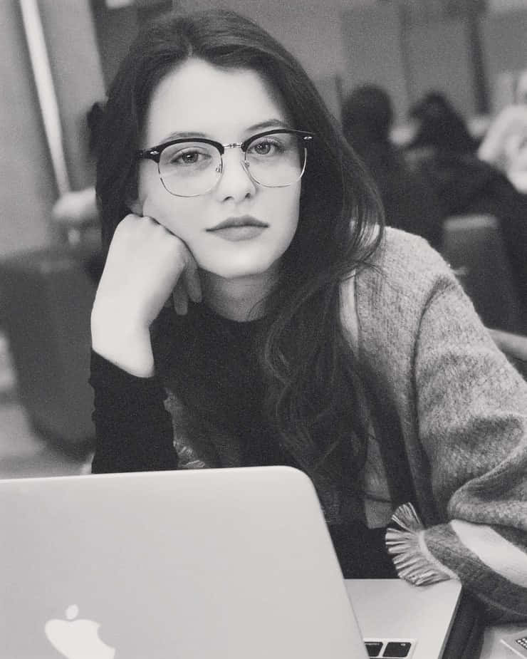 Contemplative Womanwith Laptopand Glasses Wallpaper