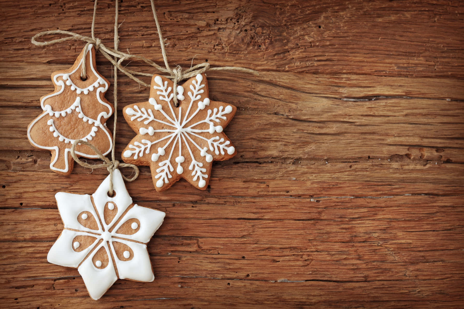 Three Gingerbread Cookies Hanging On A Wooden Background