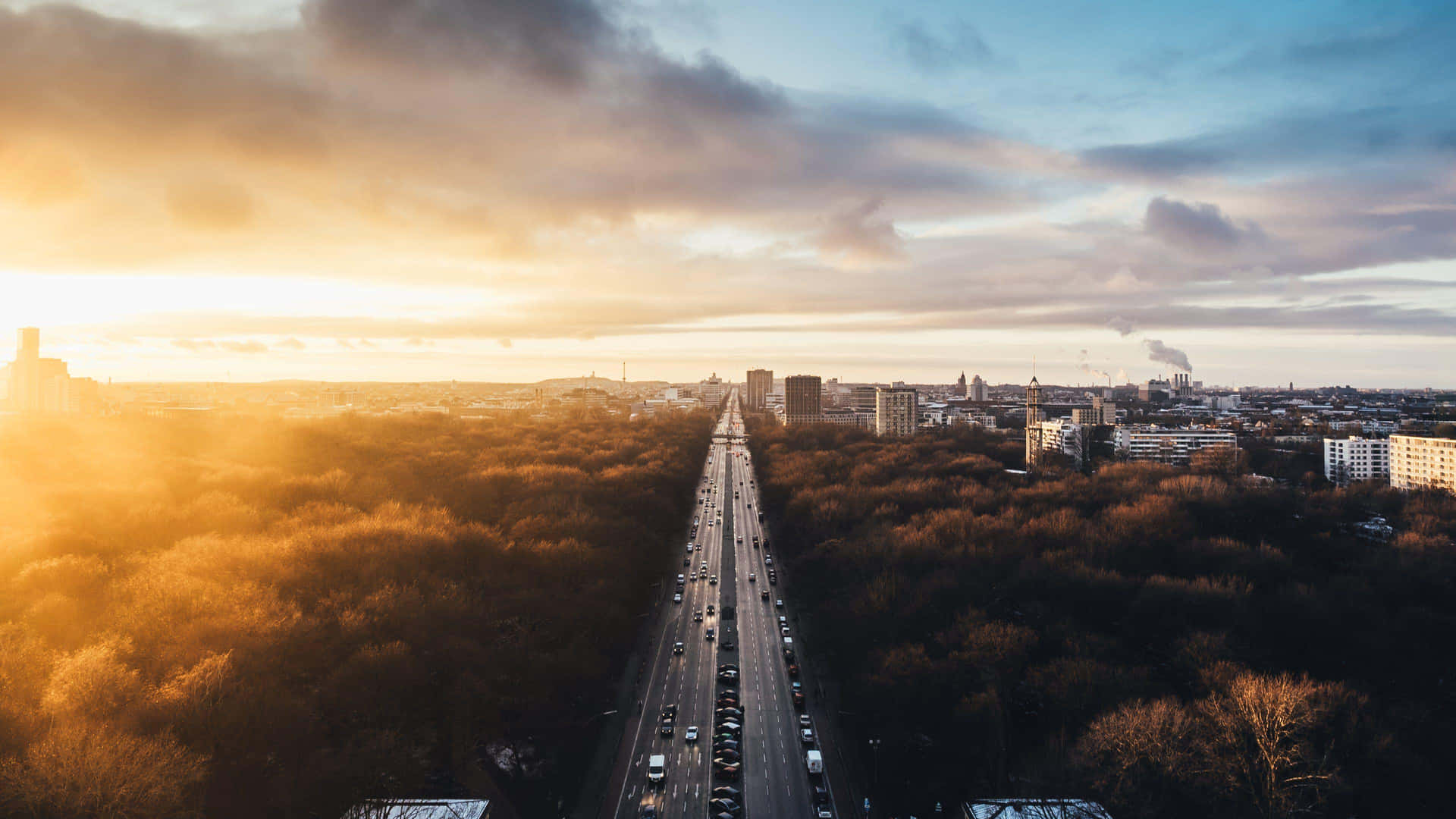 A City With Trees And A Highway At Sunset Wallpaper