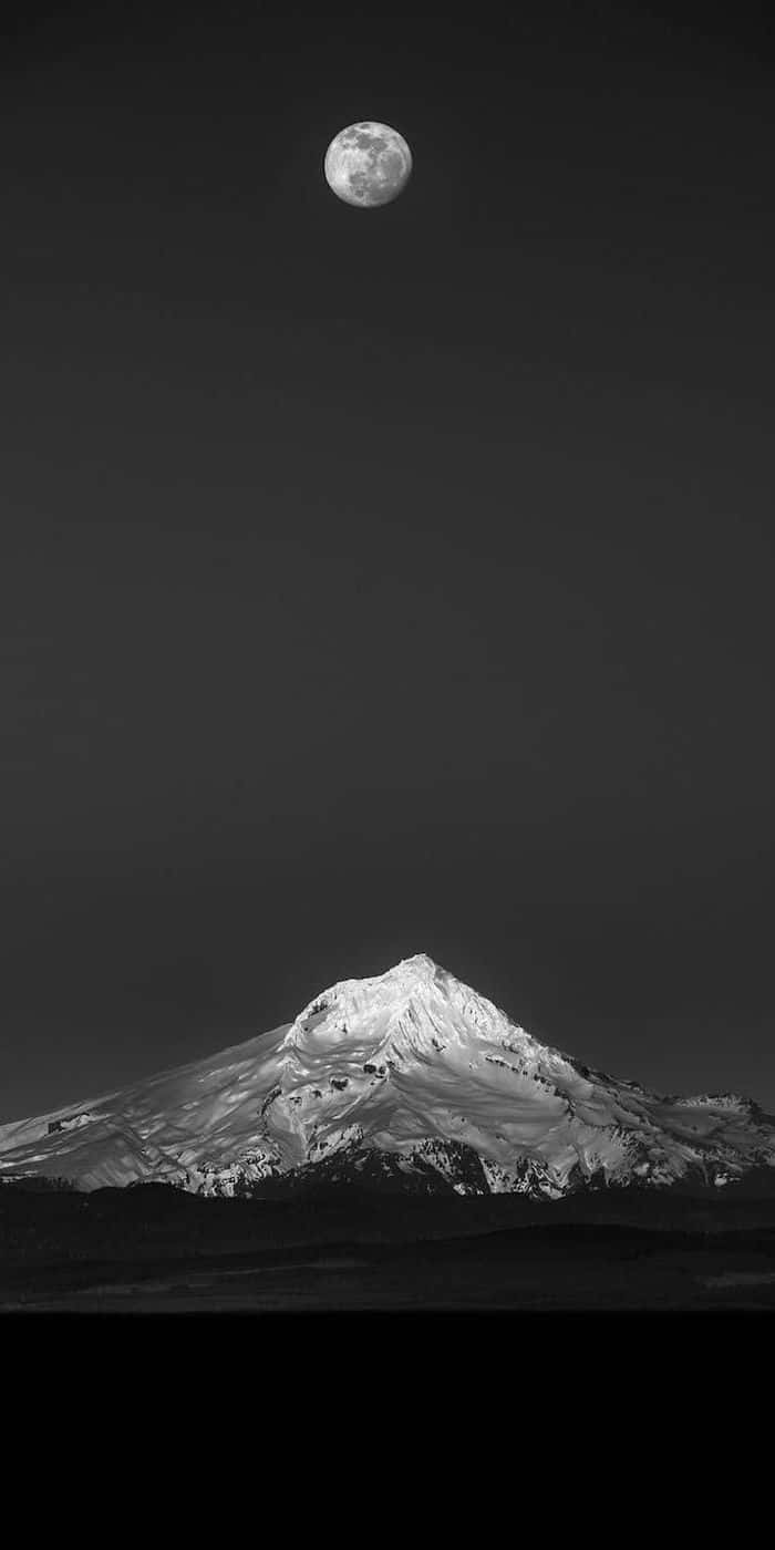 A Black And White Photo Of A Mountain With A Moon In The Sky Wallpaper
