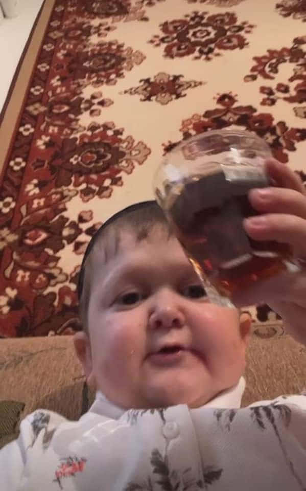 A Baby Holding A Glass Of Wine