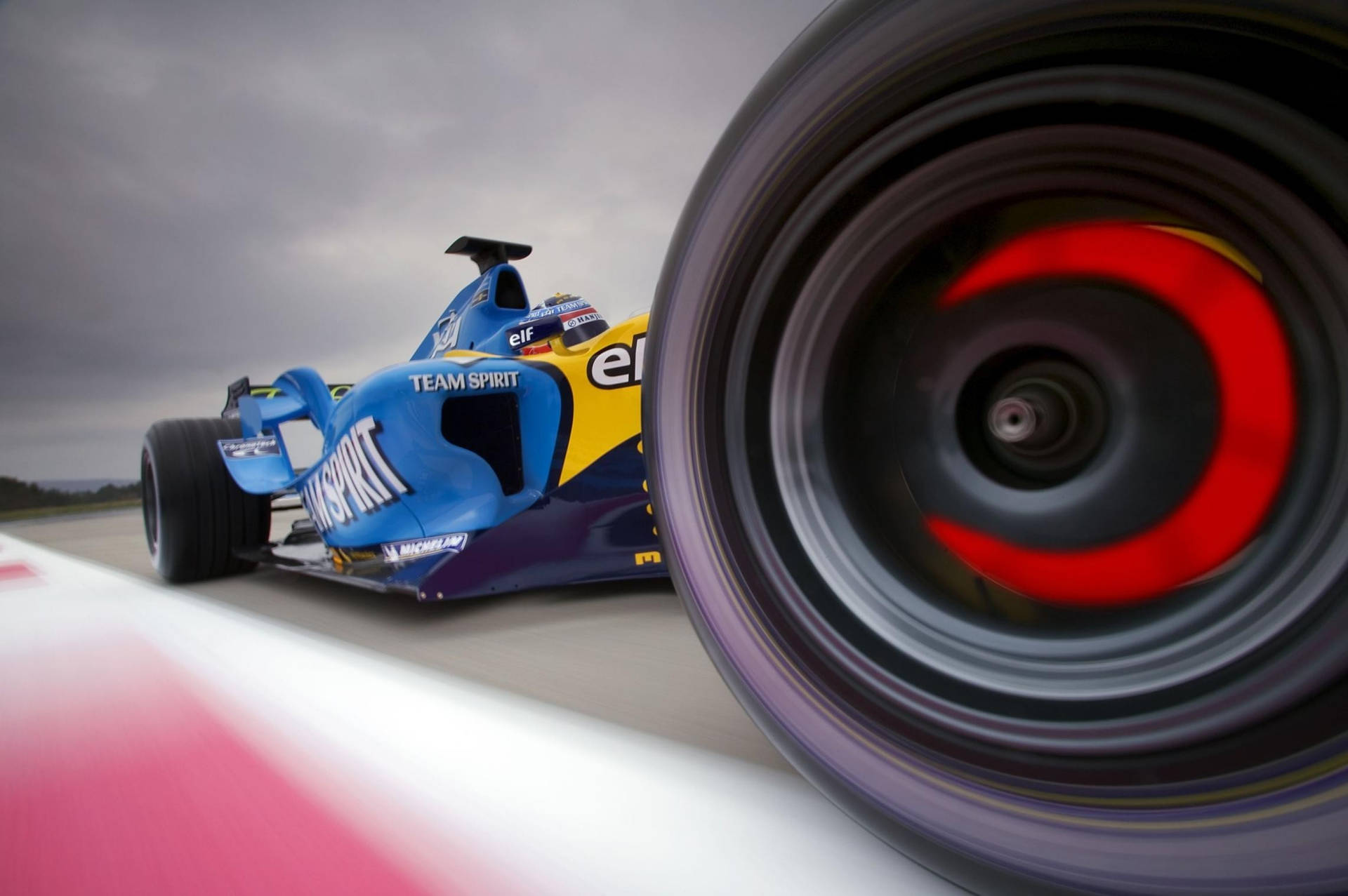 En blå racerbil med røde hjul på banen Wallpaper