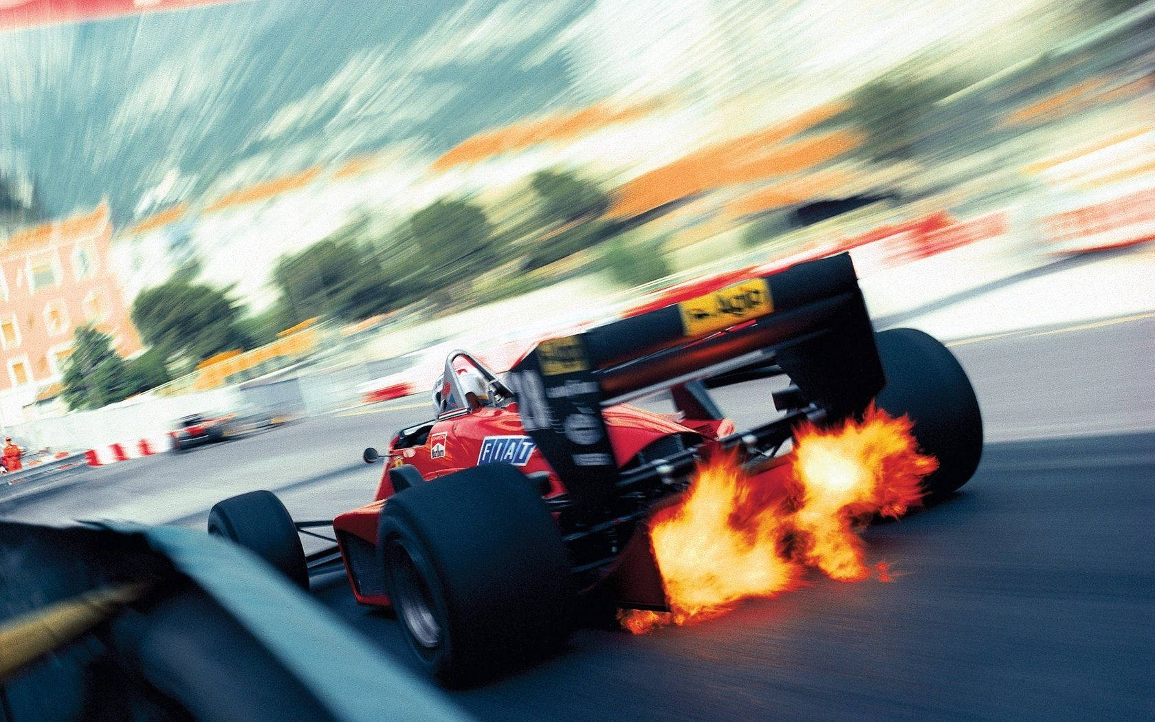 A Racing Car Is Driving Down A Street With Flames Wallpaper