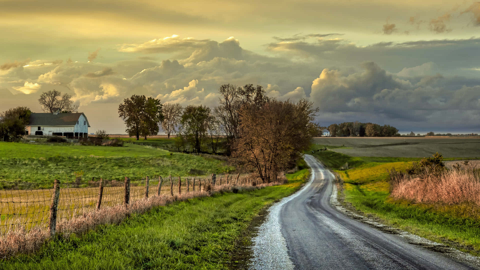 A Country Road With A Farmhouse In The Distance Wallpaper