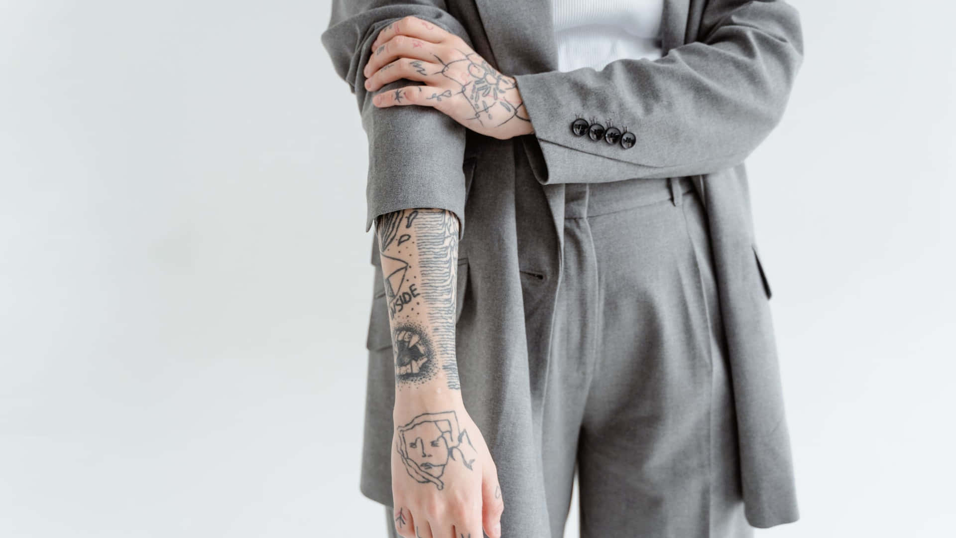 A Woman With Tattoos Wearing A Grey Suit Wallpaper