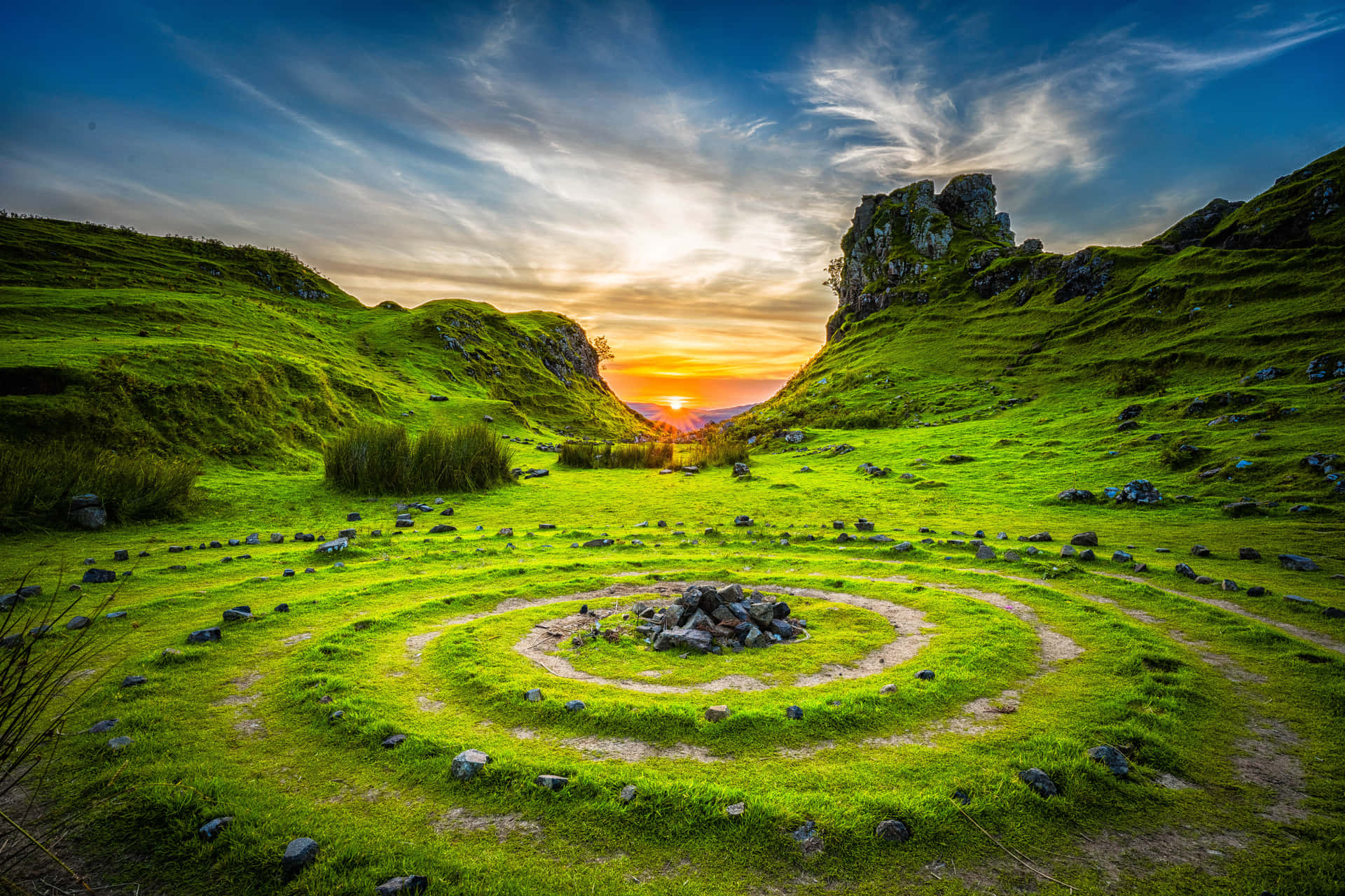 A Circular Grassy Field With Rocks In The Middle Wallpaper