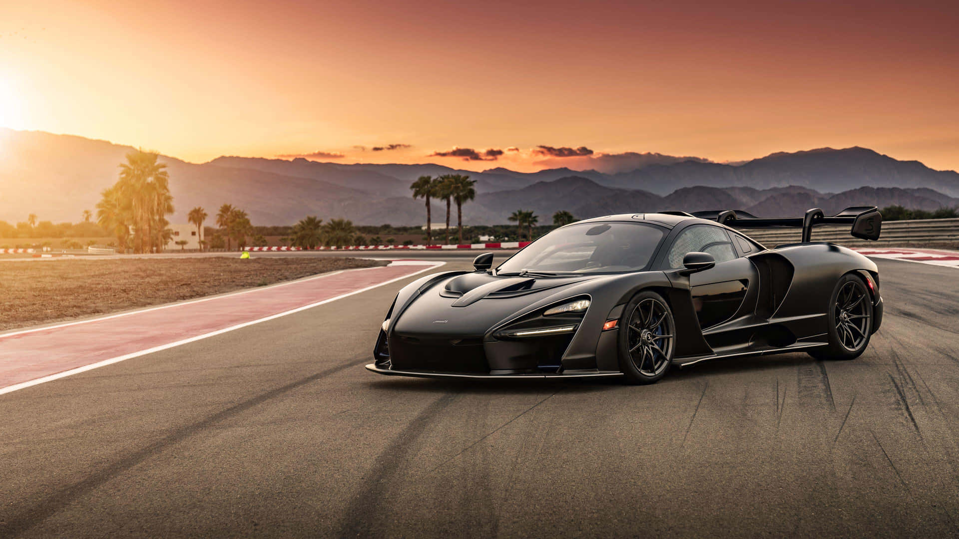 A Black Sports Car Driving On A Track At Sunset Wallpaper