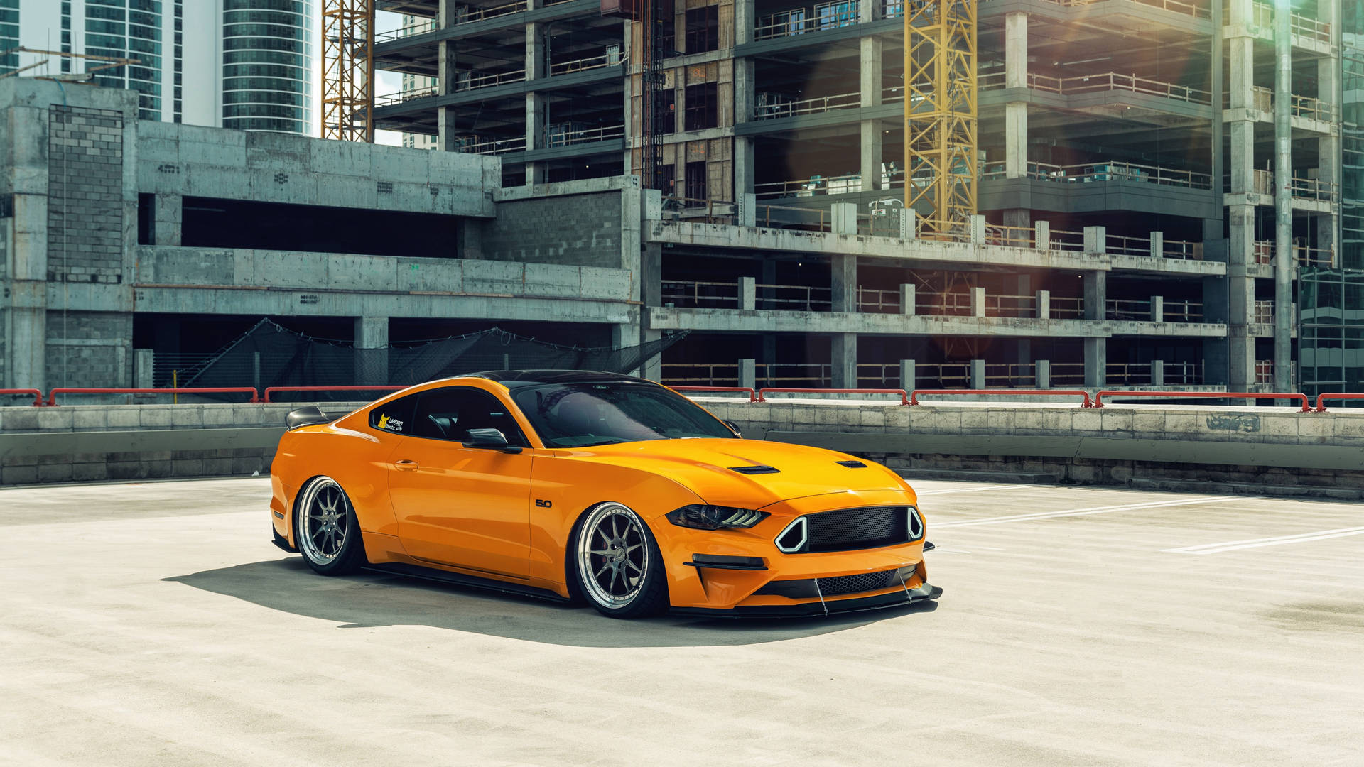 En gul Ford Mustang parkeret foran et bygning Wallpaper