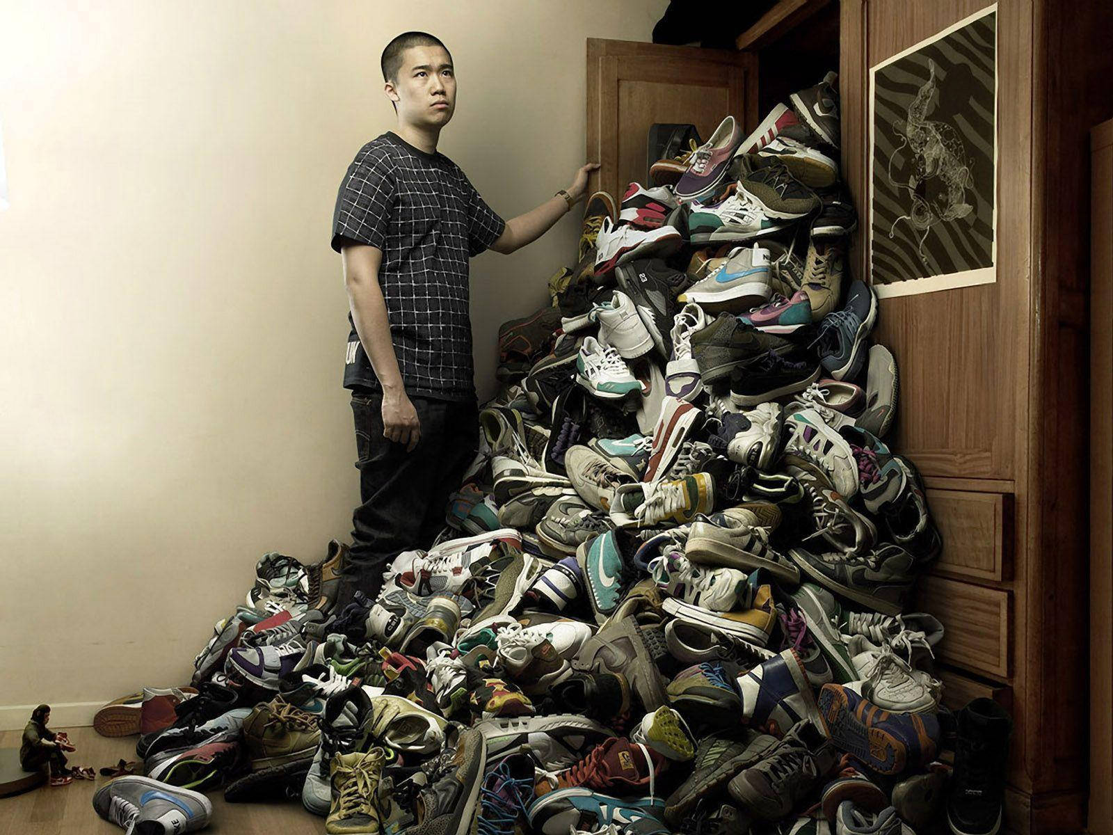 A Man Standing Next To A Pile Of Shoes Wallpaper