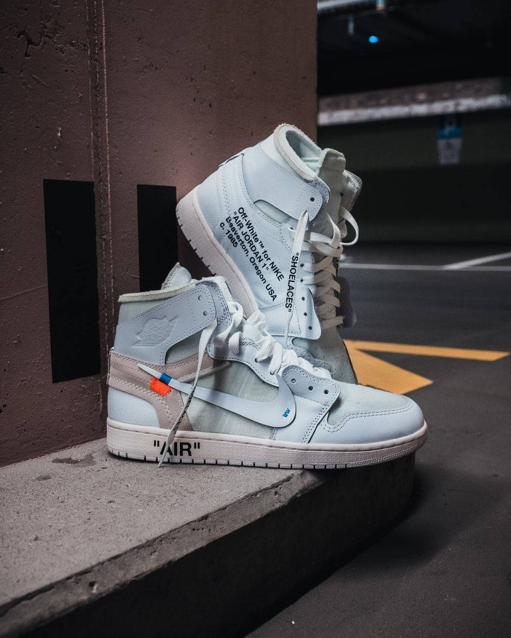 Et par hvide Air Jordan 1 High sneakers, der sidder på en betonvæg. Wallpaper