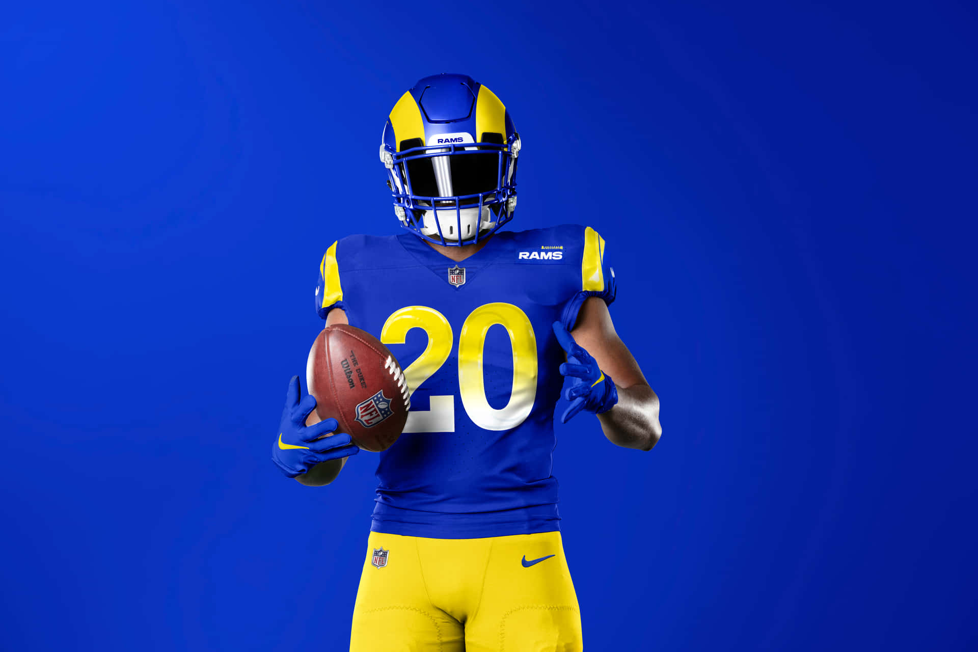 Unhombre Con El Uniforme De Los Rams Sosteniendo Un Balón De Fútbol Fondo de pantalla