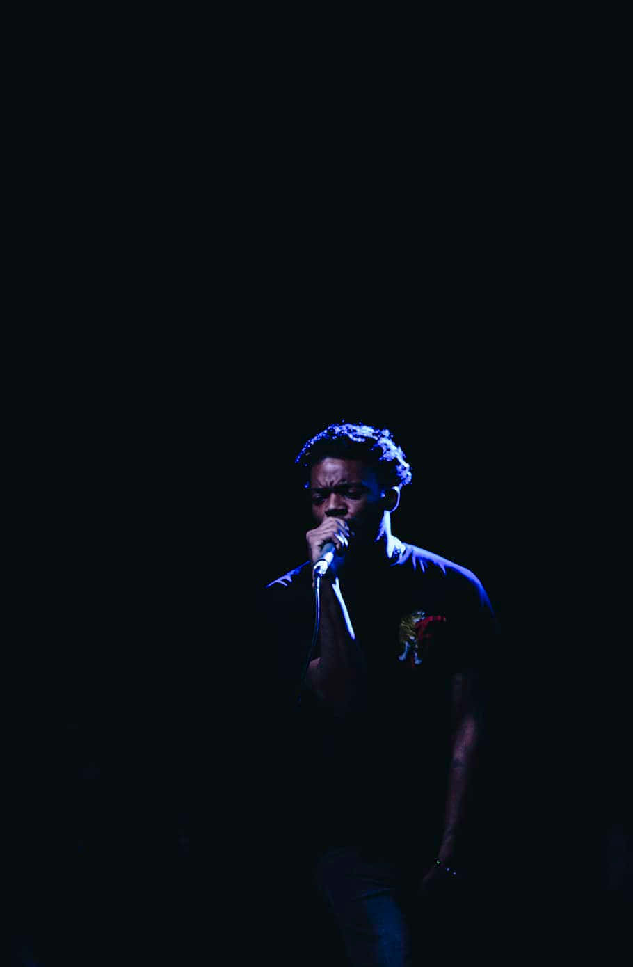 En mand synger ind i mikrofonen i mørket. Wallpaper