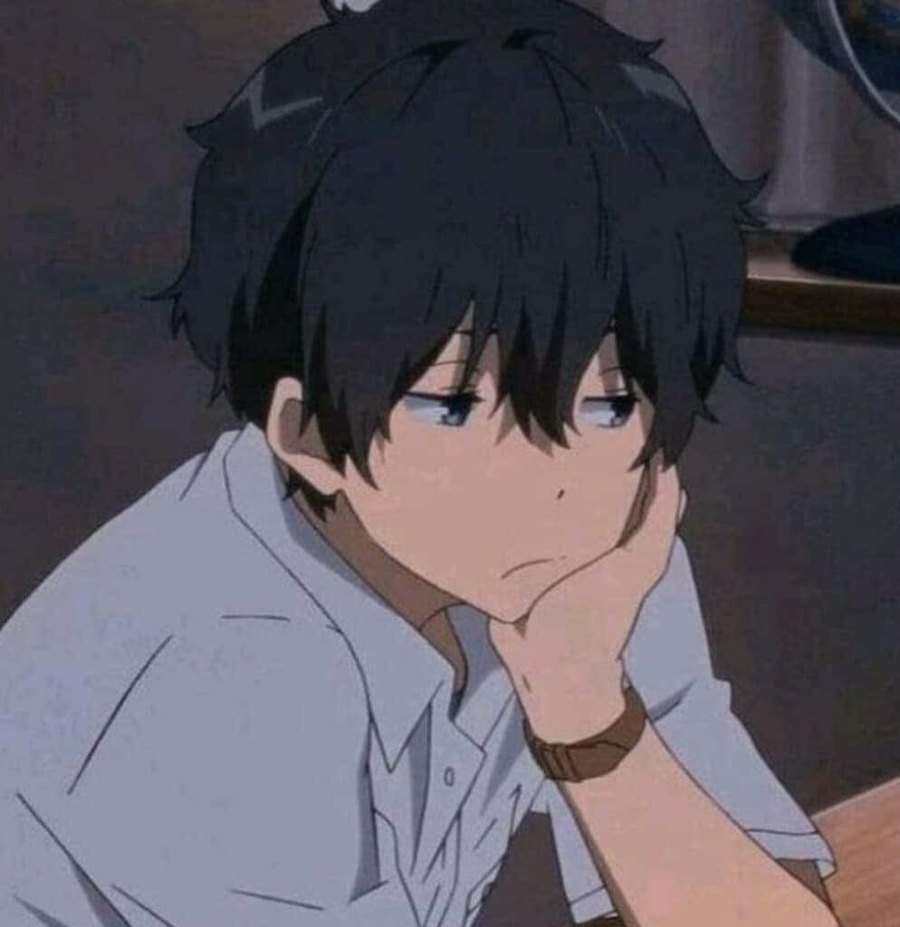a boy with black hair is sitting at a desk
