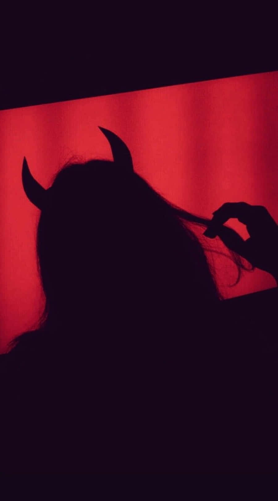 a silhouette of a woman with horns in front of a red light