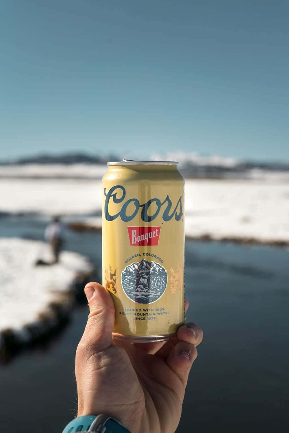 A Person Holding A Can Of Coors Light In Front Of A River Wallpaper