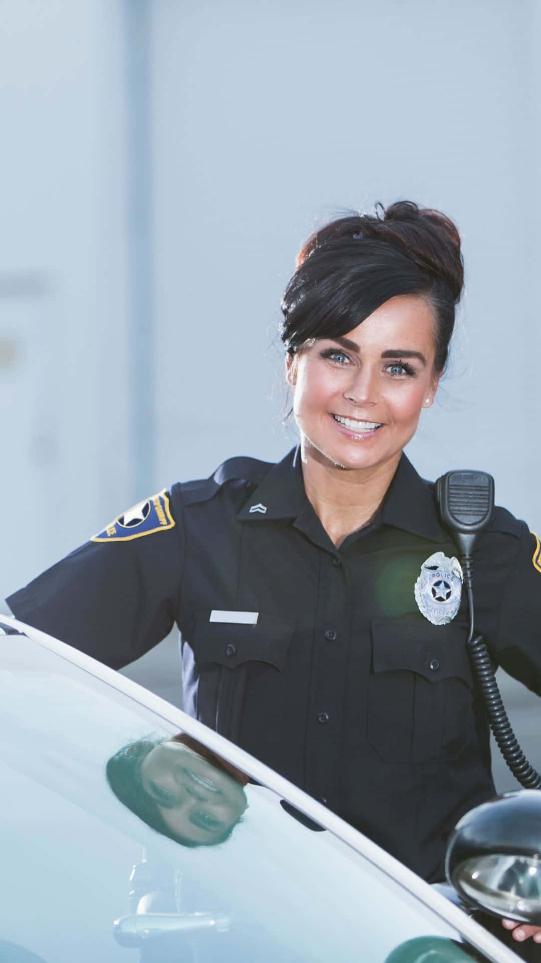 Politi betjent smilende stående ved siden af køretøj Wallpaper