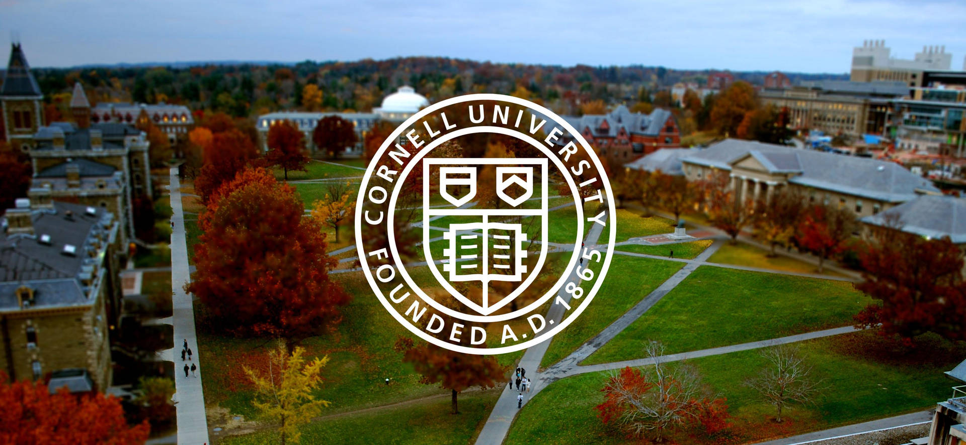 Tapetet med Cornell University Field Logo viser skolens logo mod en smuk blå himmel. Wallpaper