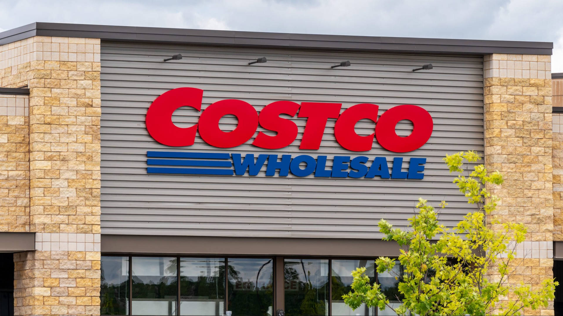 The vibrant exterior of a Costco Wholesale store showcasing a variety of plants. Wallpaper