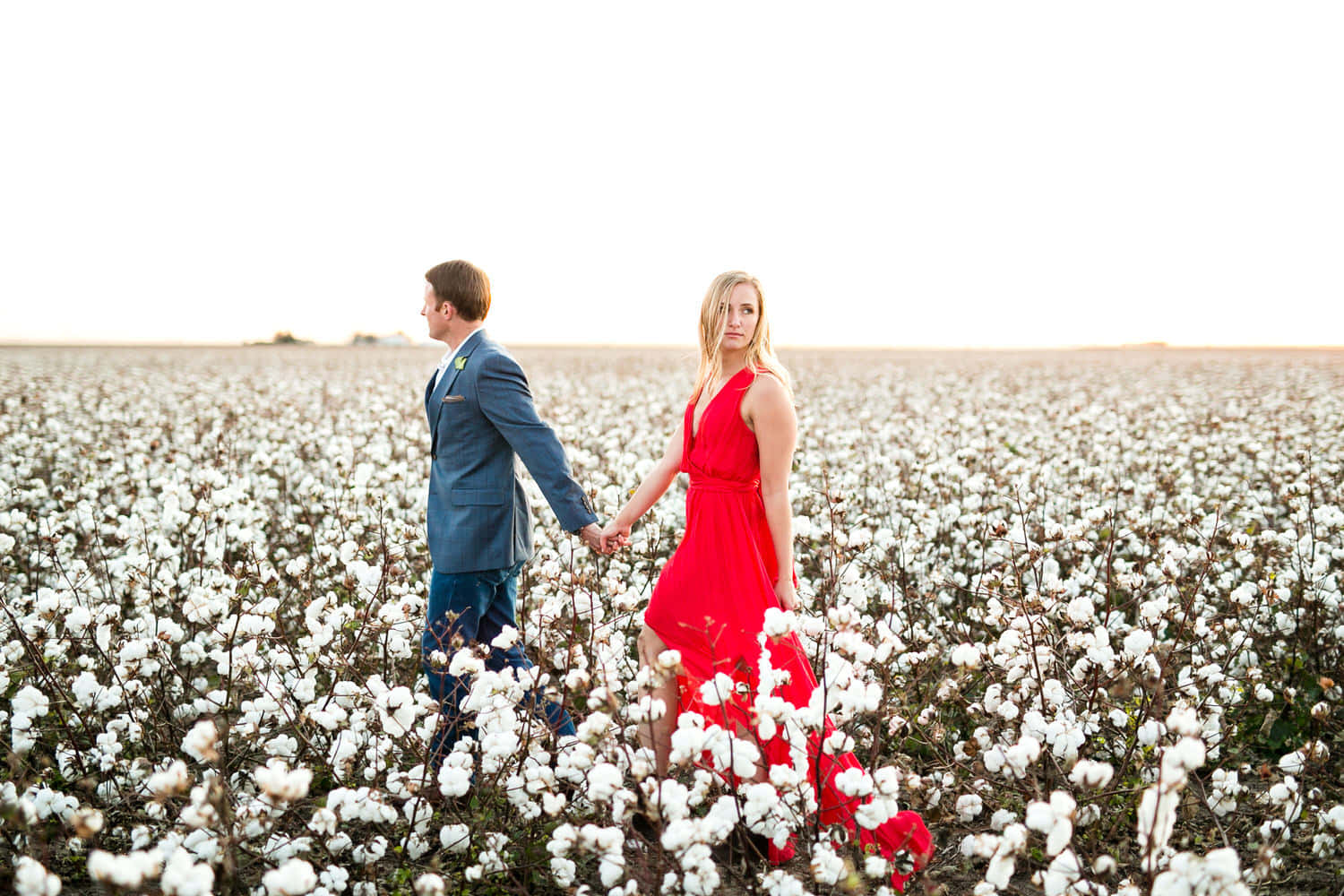 A Couple In A Red Dress Walking Through A Cotton Field