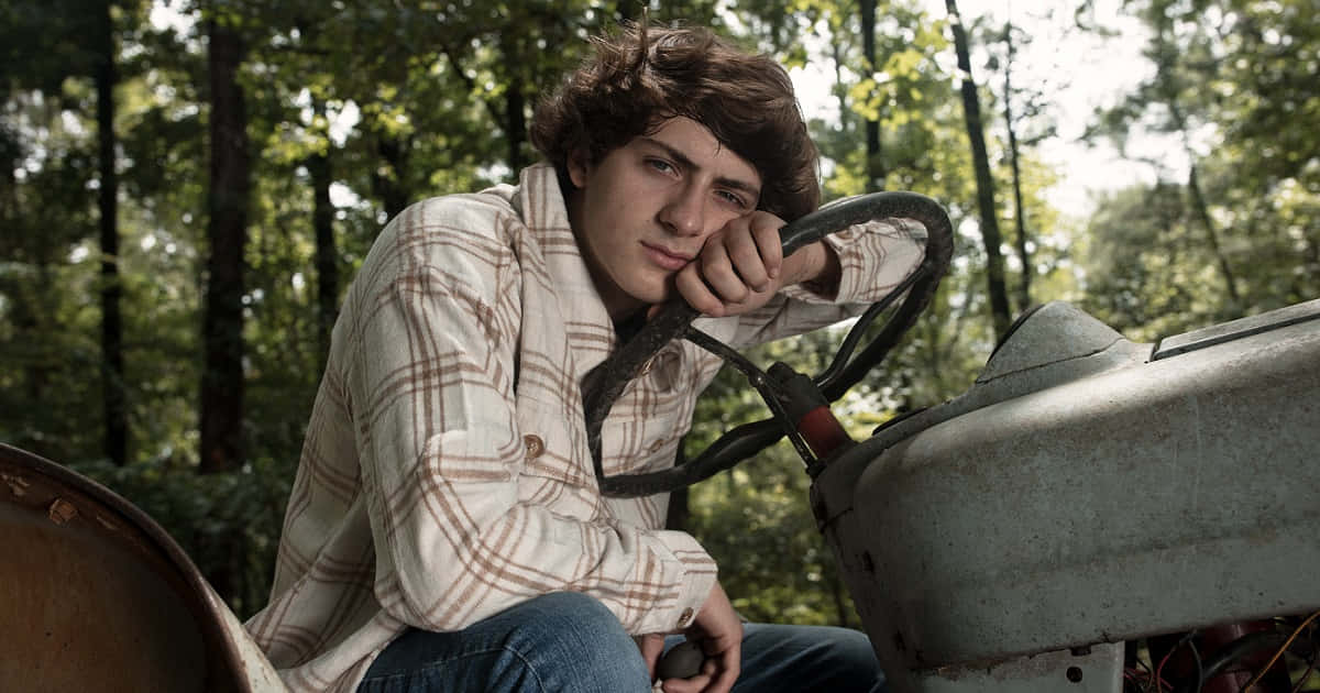 Country Boy Leaning On Tractor Achtergrond